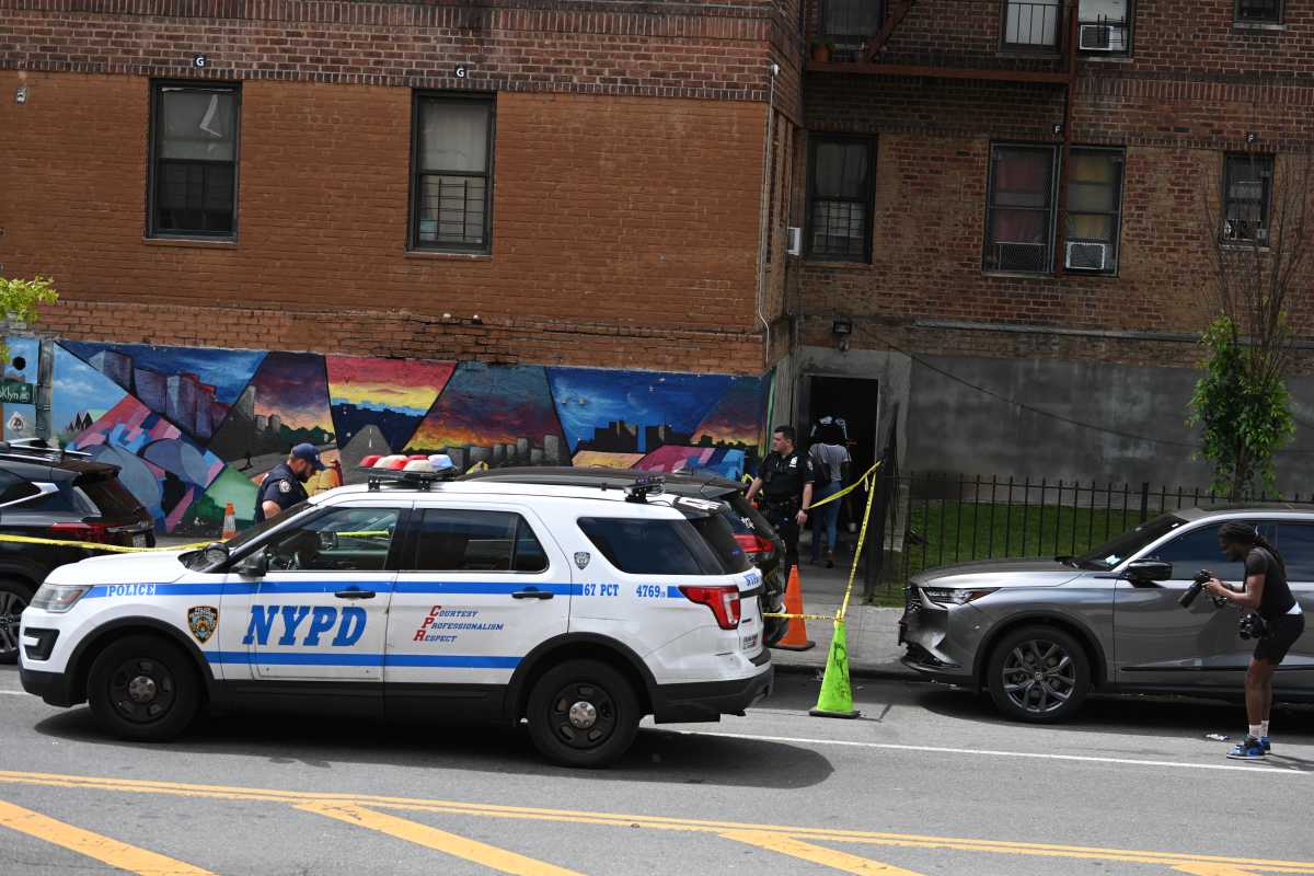 Police car and officer setting up crime scene on street where woman was shot