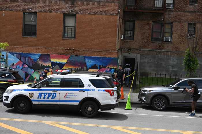 Police car and officer setting up crime scene on street where woman was shot