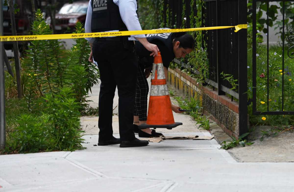 Police officers investigate scene of shooting with cone and yellow tape