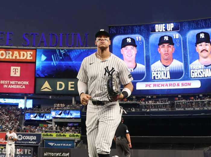 Player in white and pinstriped Yankees uniform walking off the field