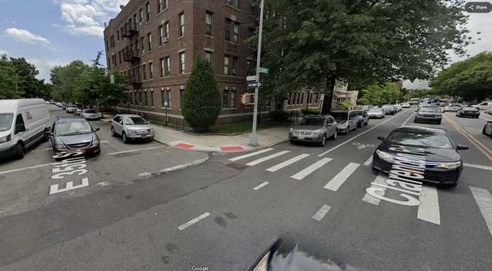 a city interesection with a building a parked cars