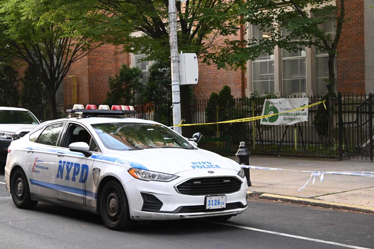 Police car with yellow crime scene tape extended near side walk