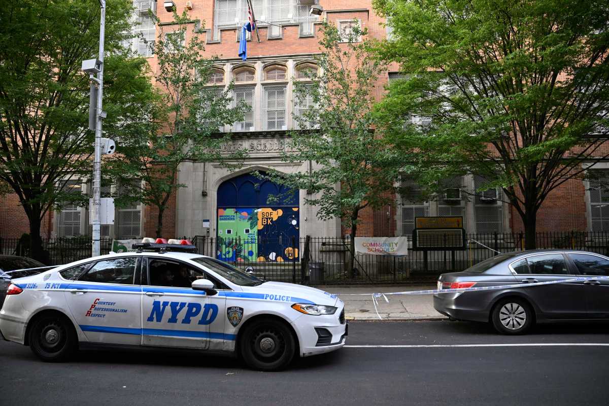 Police car with NYPD logo in front of Brooklyn public school at crime scene