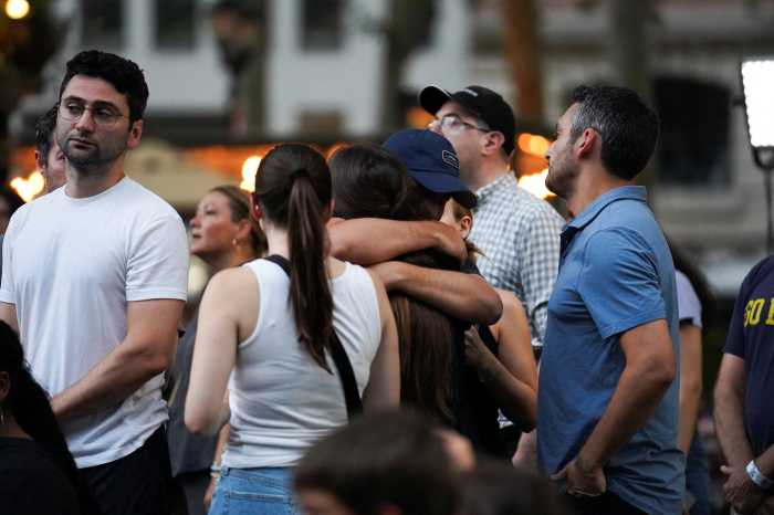 people embrace during a candlelight vigil in Bryant Park