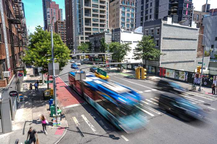 Expert Analysis | After one year of NYC congestion pricing, the mobility jury is still out 2 A bus speeds past a congestion pricing gantry in Midtown Manhattan.