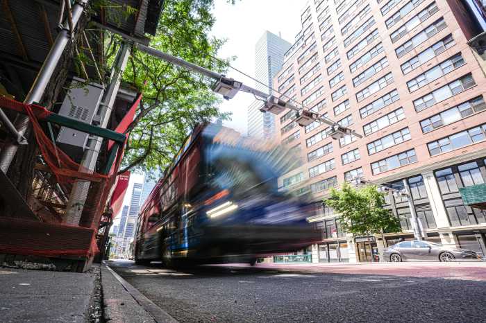 An MTA bus passing under a congestion pricing gantry in Manhattan