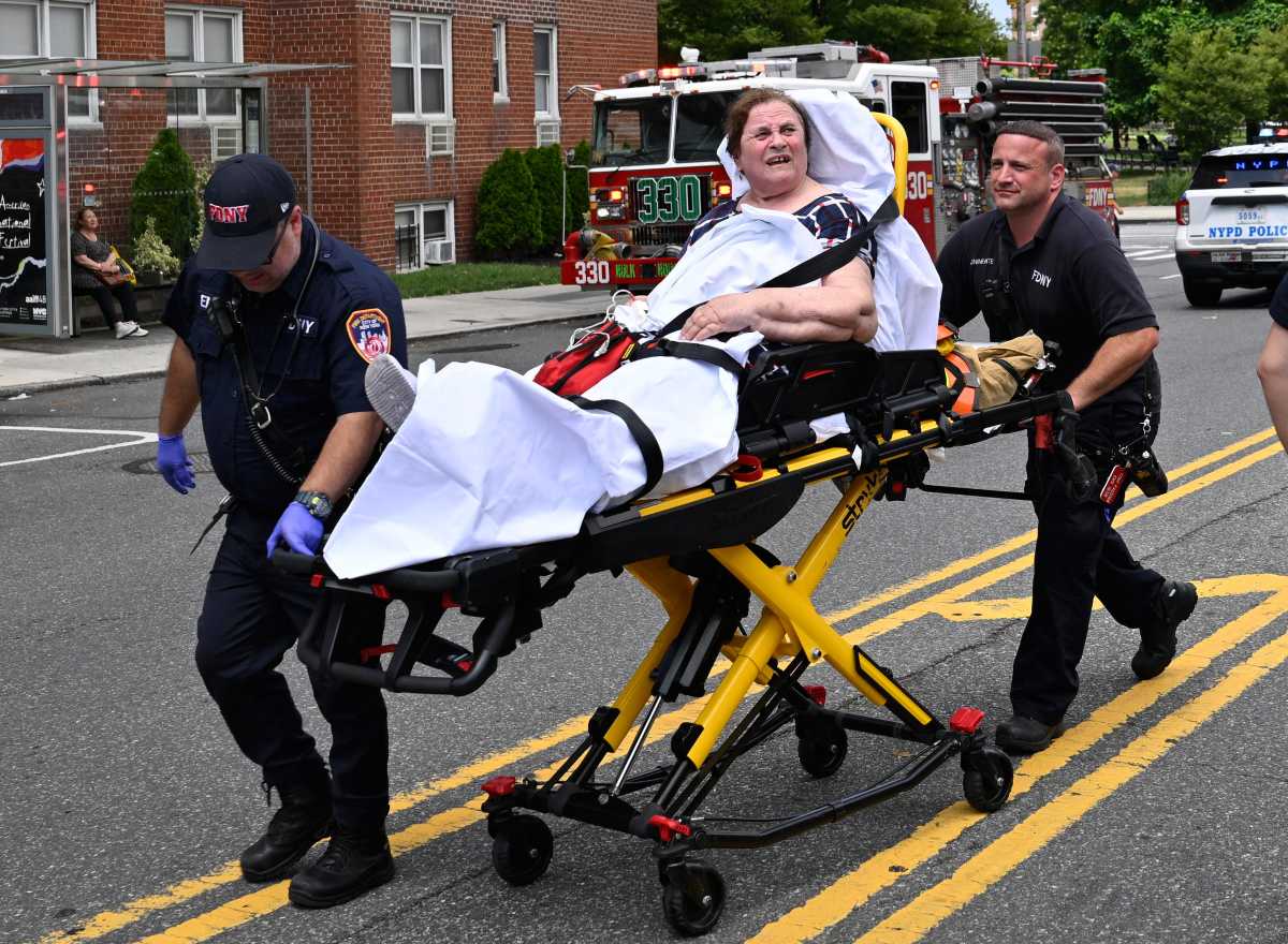 NYC EMTS working to wheel woman on stretcher during fire