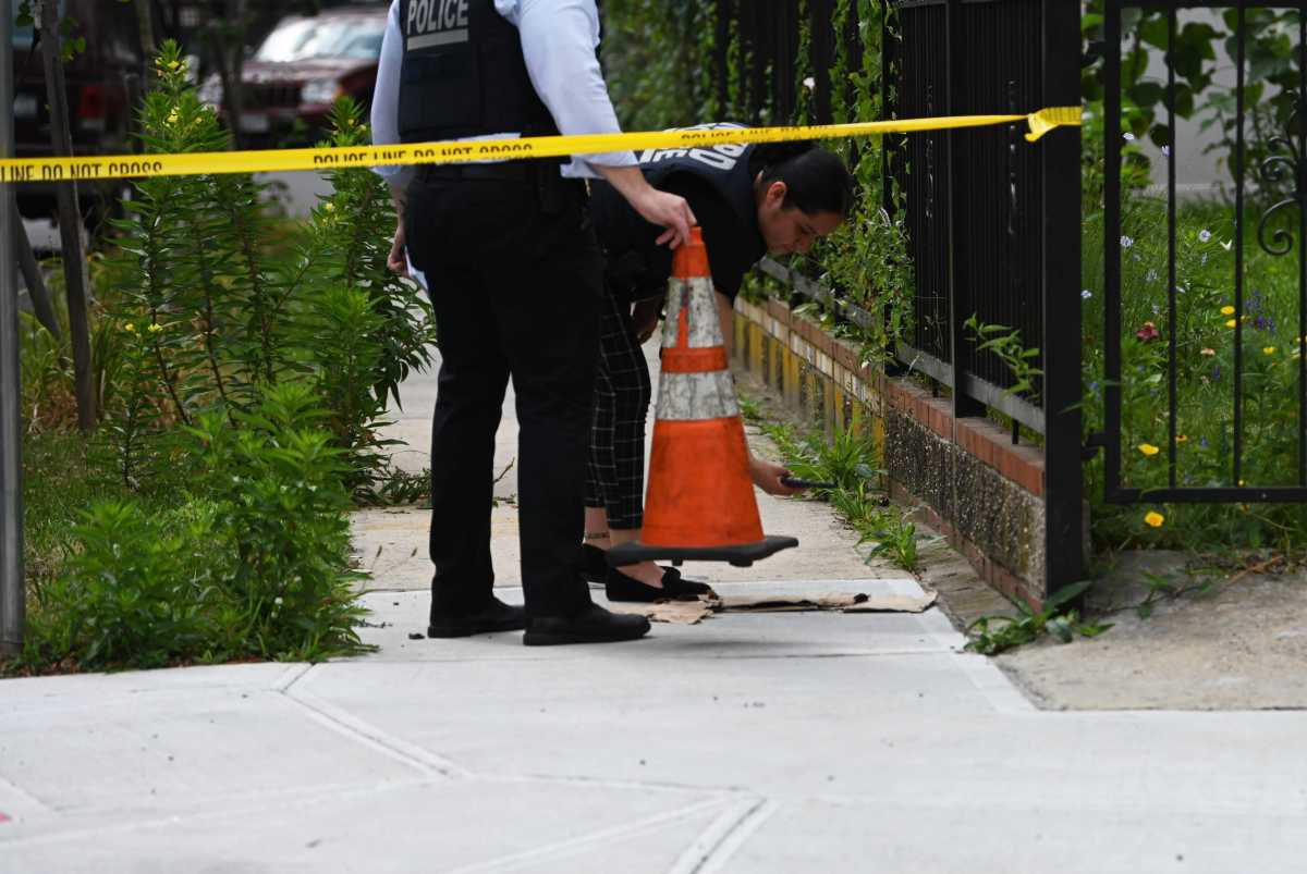 Police officers examine evidence of a shooting with yellow crime scene tape stretched