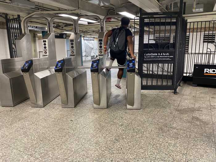person wearing a backpack jumping a sturnstile in a Brooklyn subway station