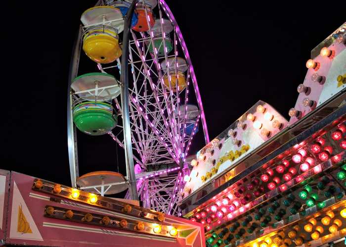 Ferris wheel and colorful lights at night at a county fair.