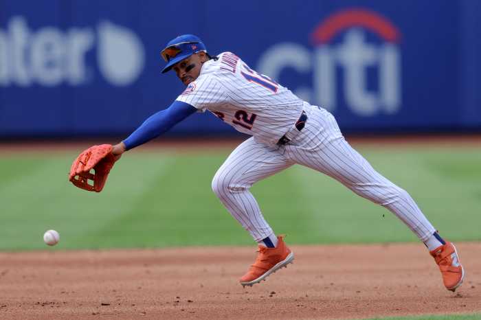 Francisco Lindor: Baseball player in white uniform, blue hat stretches to reach a ground ball