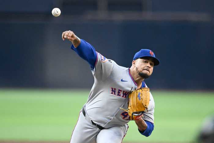 Mets pitcher in gray uniform and blue hat throws baseball