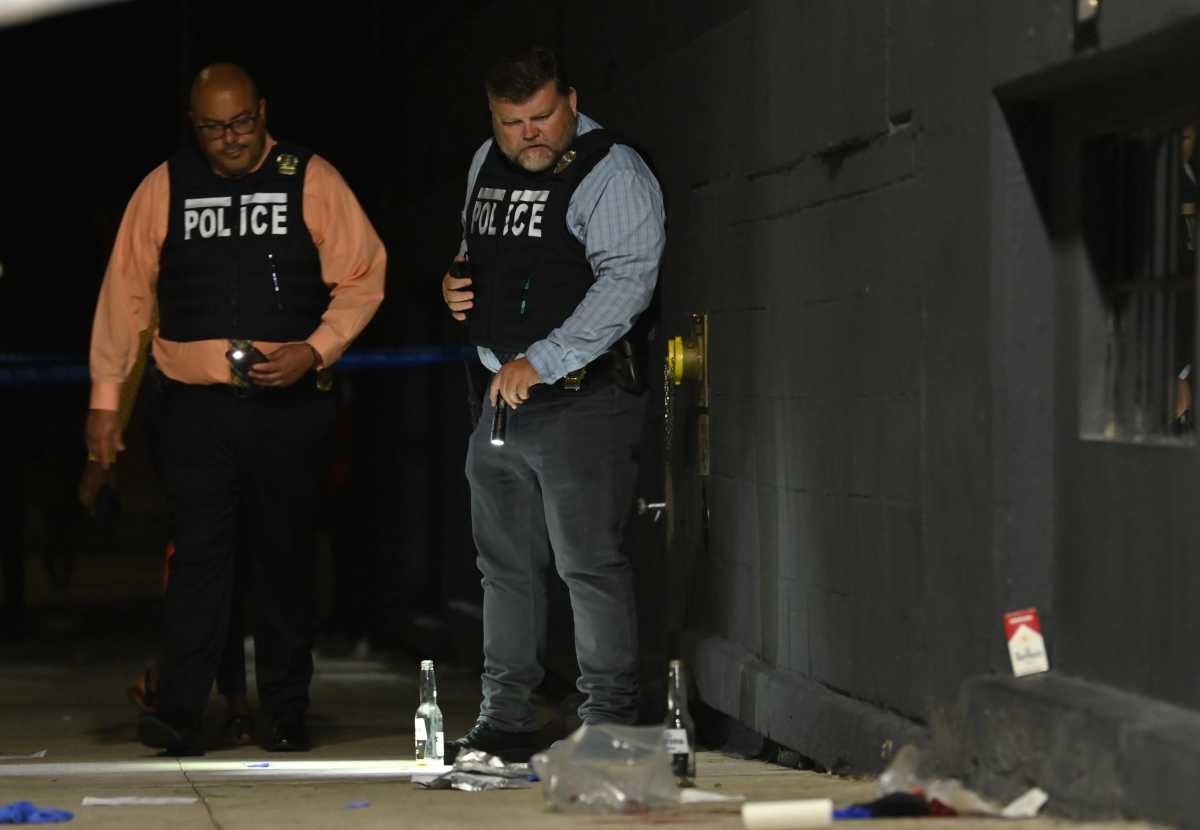 Police officers in NYPD vests examine scene where person was shot