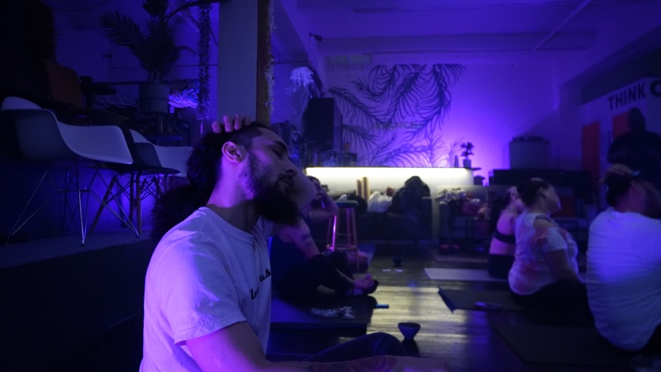 When weed meets wellness: a look inside HighYoga’s mindful movement classes 2 People in dark room with purple hue doing yoga and cannabis