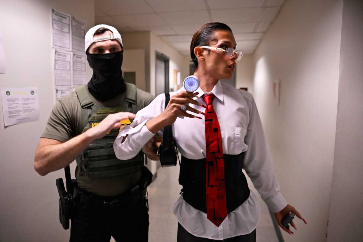 two people in a hallway, one of them being brought out by a federal agent