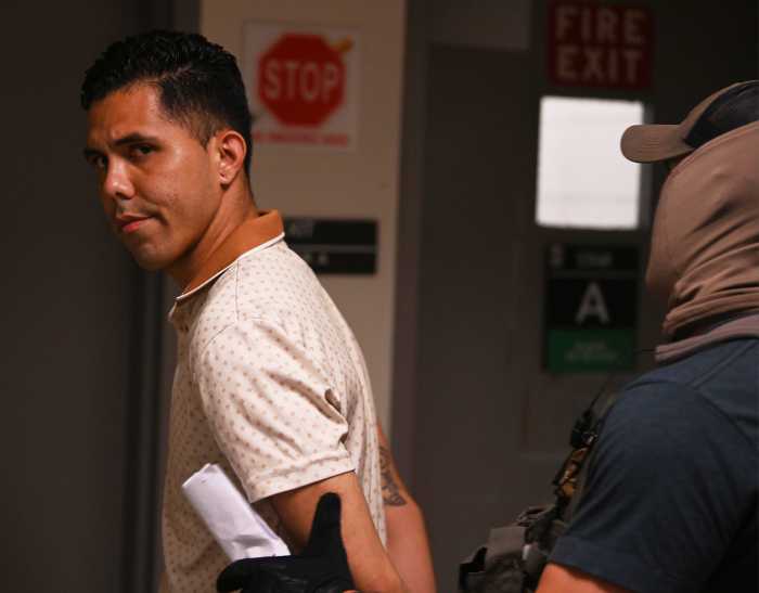 a man in a white shirt getting arrested