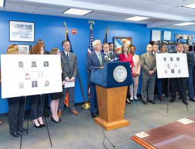 a group of people in a room behind a podium discussing a NYS DMV scam