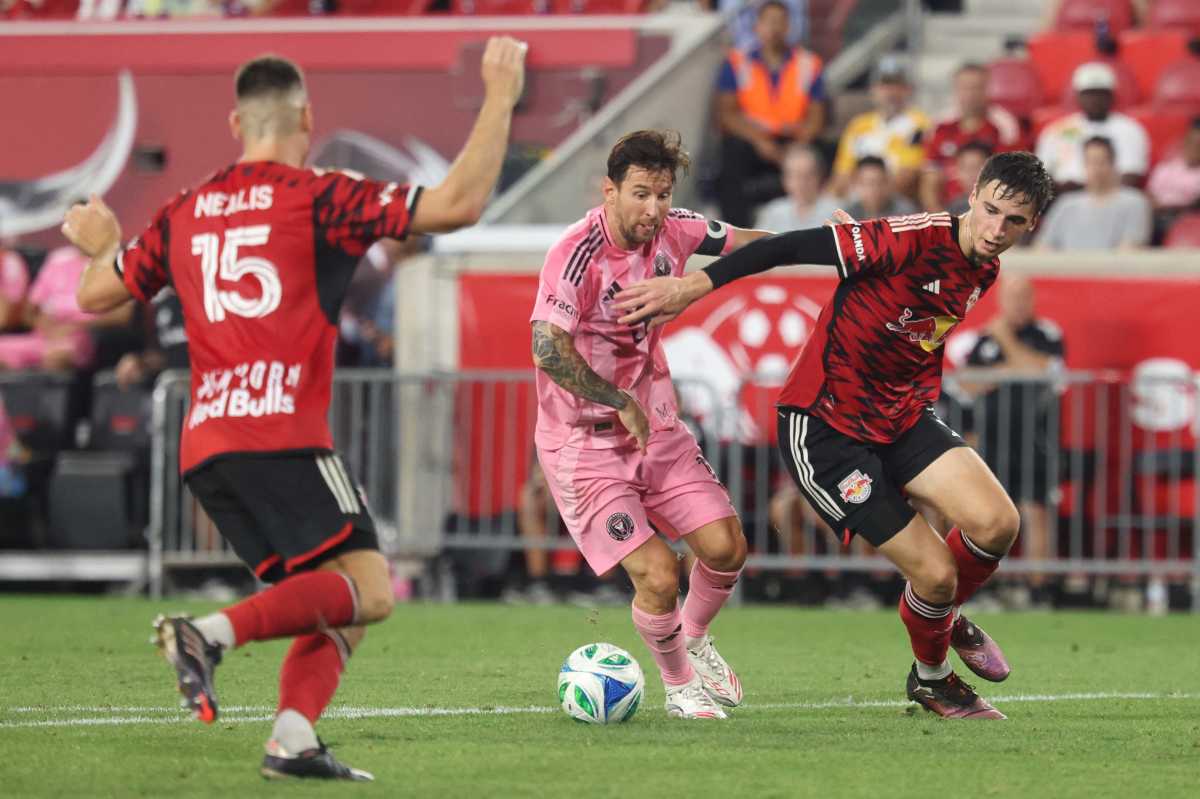 Lionel Messi: Man in pink uniform dribbles soccer ball between two men in red uniforms