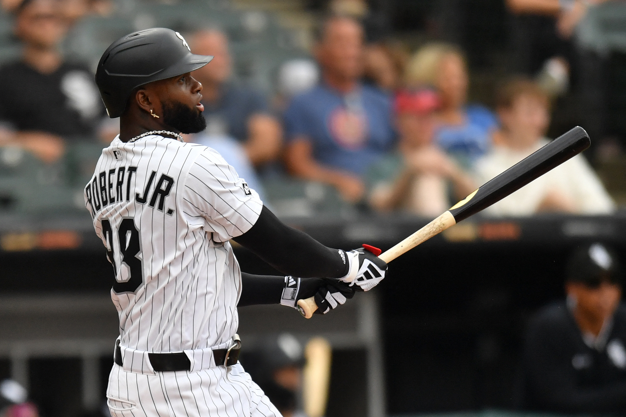 Luis Robert Jr. Mets trade: Baseball player in white uniform and black helmet watches ball after swinging bat