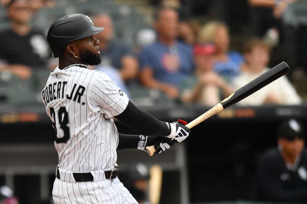 Luis Robert Jr. Mets trade: Baseball player in white uniform and black helmet watches ball after swinging bat