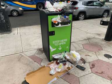 a public trash can that is overstuffed with garbage
