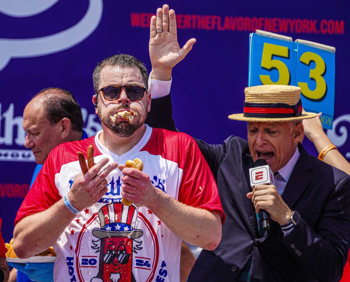 What you need to know about the Nathan's Famous Hot Dog Eating Contest 2 man eating hot dogs while man in microphone sings his praises