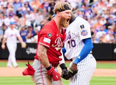 Baseball player in red uniform celebrates after hitting triple.