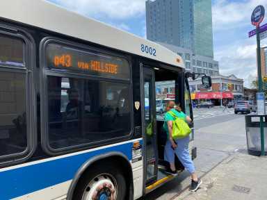 woman boarding a NYC bus during the day