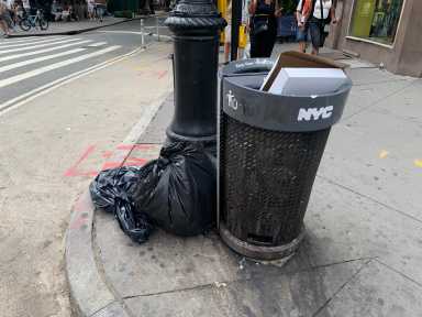 Black garbage bags sat next to several full litter baskets on corners near NYC streets, including this one on Seventh Avenue in the West Village.