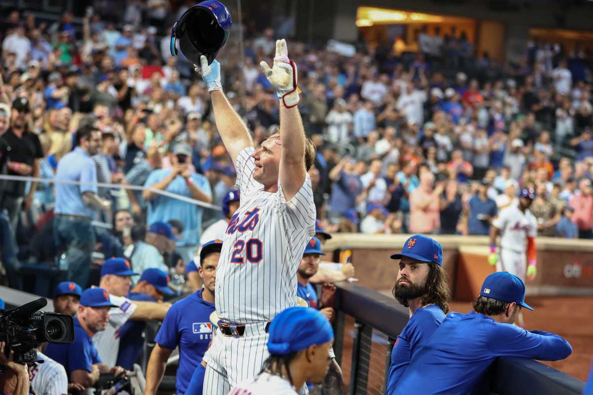 Pete Alonso 253 curtain call: Man in white uniform raises arms in celebration in baseball dugout
