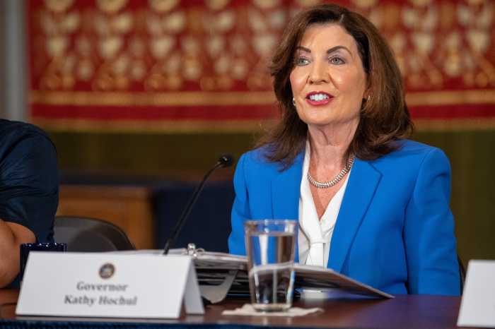 a woman sits at a table. Governor Kathy Hochul