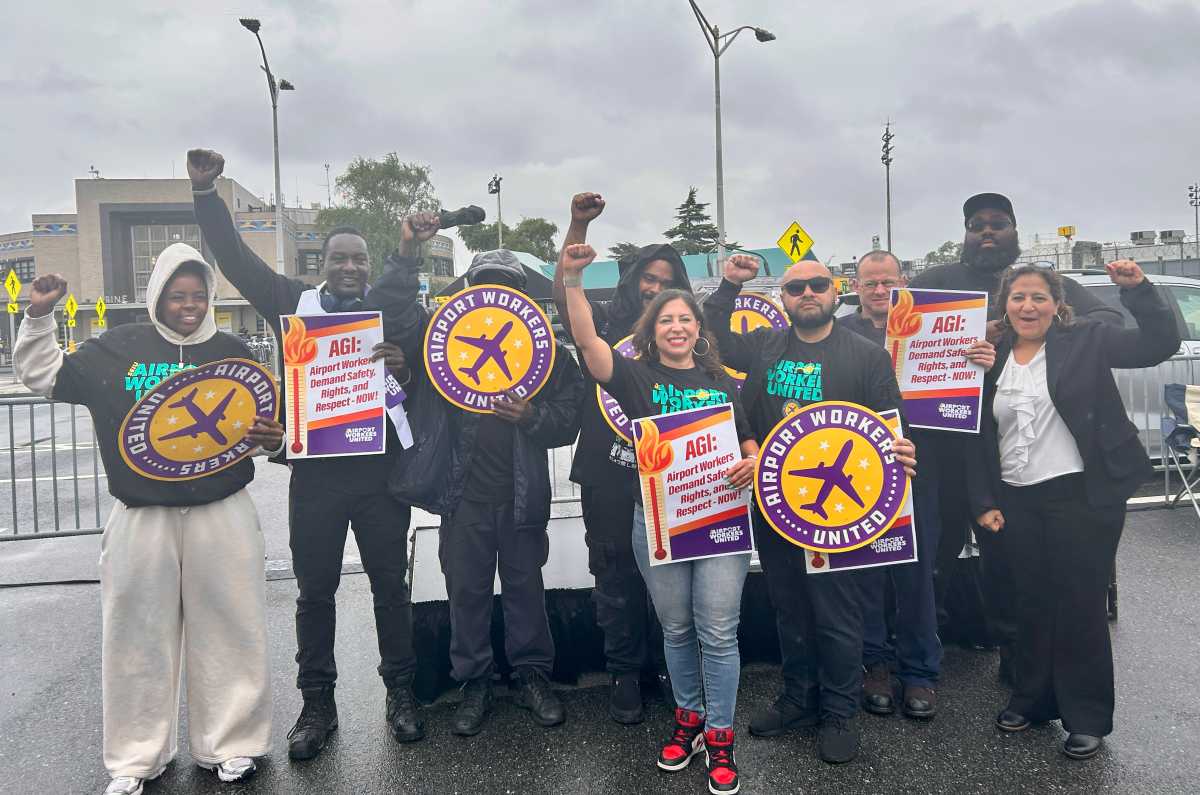 people holding signs in the rain at an airport