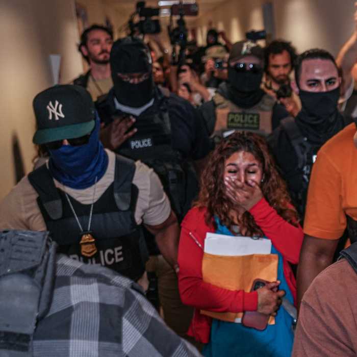 woman in tears as ICE agents arrest and escort her in hallway