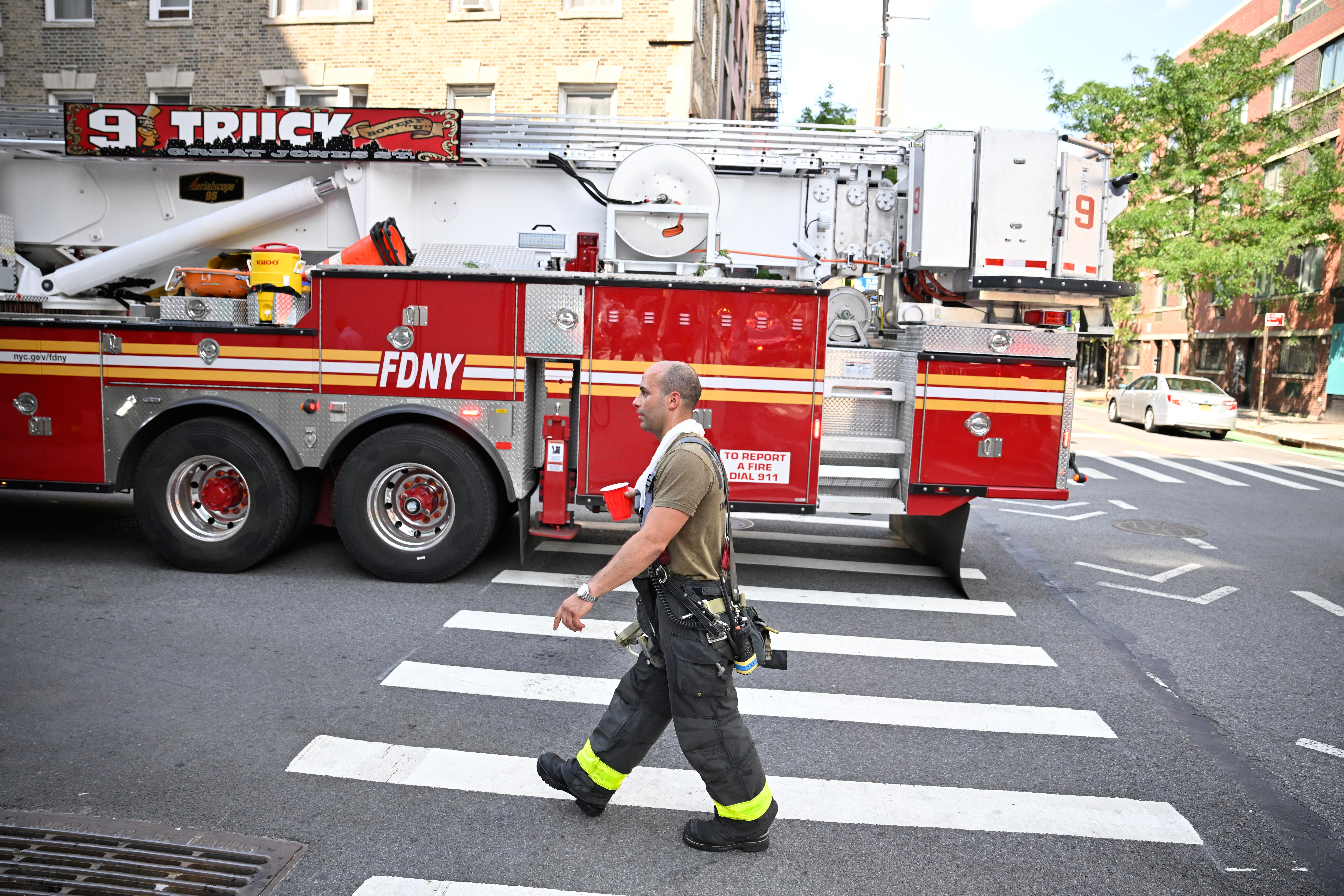 A firefighter works to beat the heat as temps were in the mid 90's during an afternoon blaze in the lower East side on Monday, July, 28.