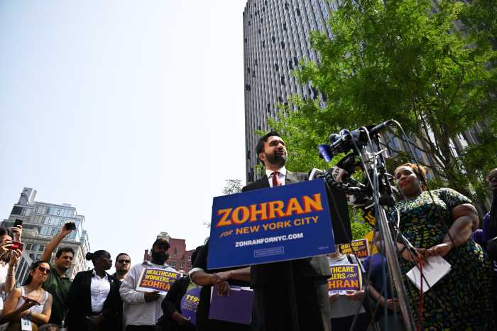 man in suit at Zohran Mamdani rally speaking at press conference