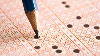 Student filling out answers to a test, test scores have gone up in new york city