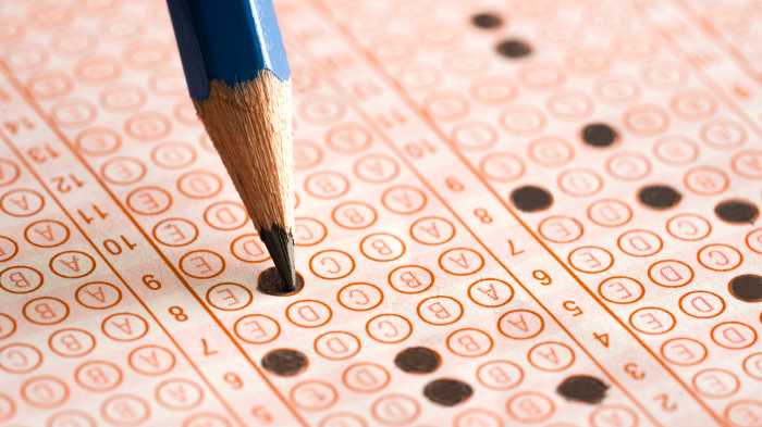 Student filling out answers to a test, test scores have gone up in new york city