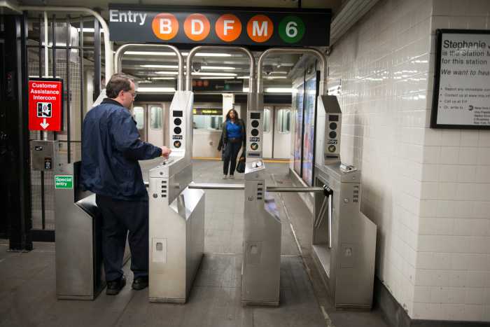 "New York City, United States - October 27, 2012: A man entering a New York City subway station swipes his metro card at the turnstile. In the background a woman has just exited a train and is walking towards the exit."