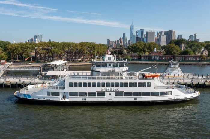 a white ferry in the waters near Governors Island during the day