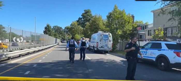 NYPD officers stand near the cordoned-off scene on the Whitestone Expressway service road in Queens on Friday