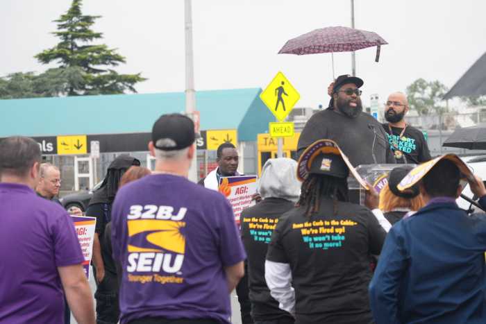 group of people watching a man speak at a podium outside