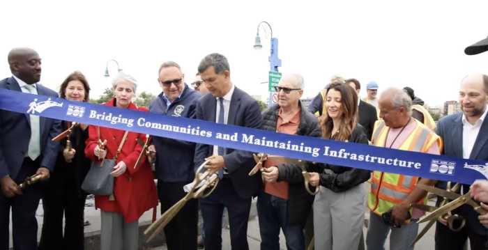 group of people near a bridge cutting a ribbon