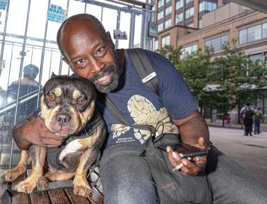 man smiling with his dog, reunited after being stolen from bronx train