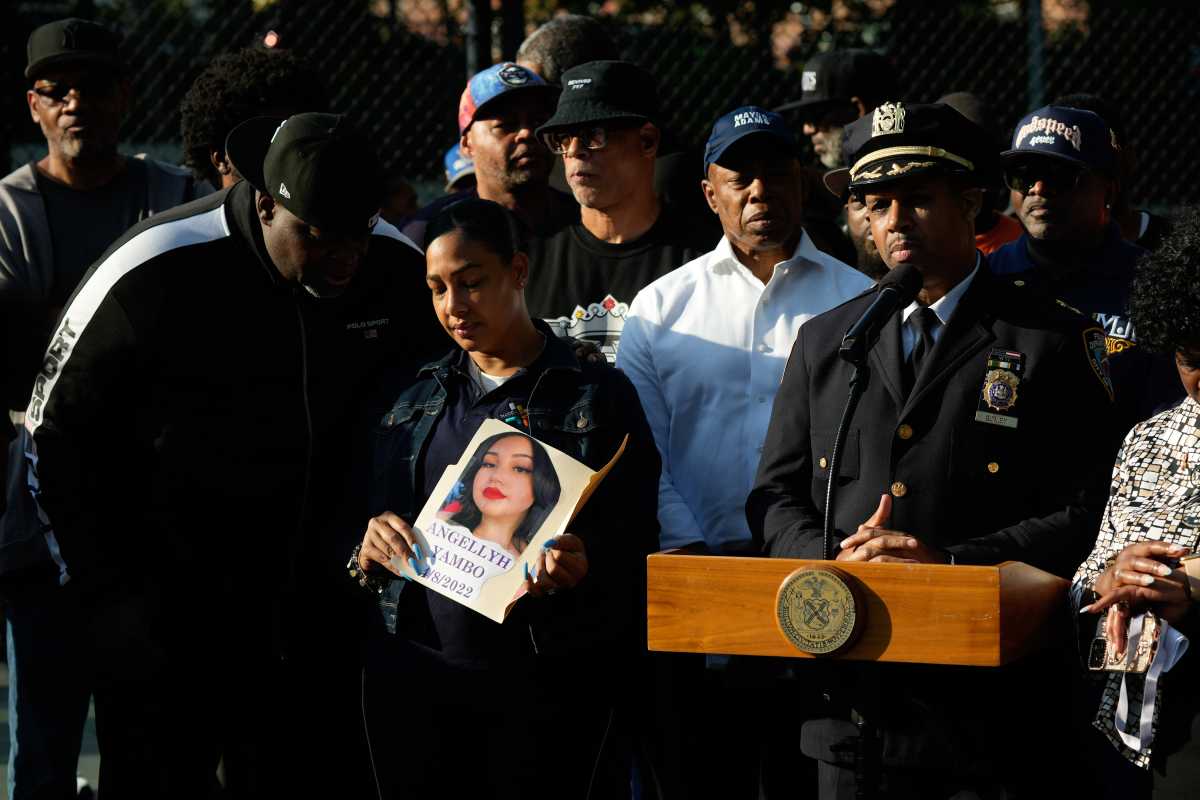 NYPD executive speaking at podium surrounded by people and mayor talking about shootings