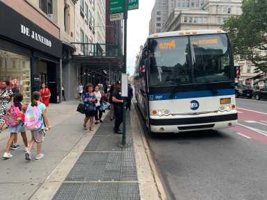 people waiting on line to board an express bus to Staten Island during the day