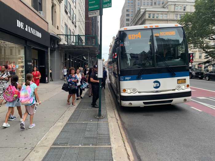 people waiting on line to board an express bus to Staten Island during the day