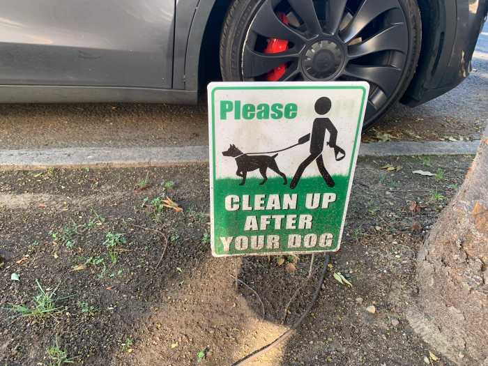 a sign posted into a mound of dirt on a city street