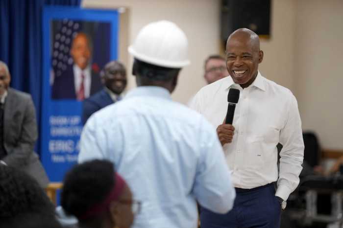 man smiling while holding microphone and talking to person in hard hat