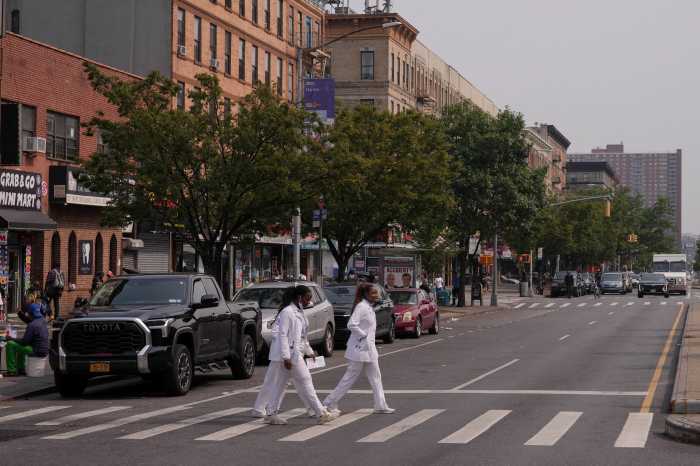 people dressed in white crossing a street in Harlem during a Legionnaires' disease outbreak.