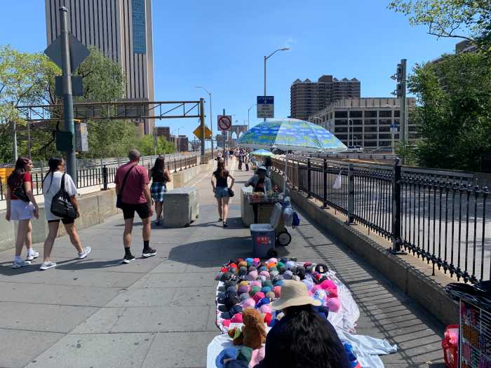 Defying a NYC ban, illegal vending thrives on iconic Brooklyn Bridge this summer 2 people walking on the Brooklyn Bridge during the day